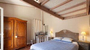 Ein Schlafzimmer mit einem Bett, einem Holzschrank, Nachttischen und einer Bank.