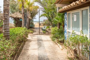 A pathway leading to a building with a gate, surrounded by greenery and palm trees. - Villa 'Fronte Mare Liolà - 4 guests' with Sea View, Private Beach Access (Scicli)