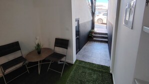 Ein Flur mit einem Sessel, einem kleinen Tisch mit einer Pflanze und einer Treppe, die nach draußen führt.