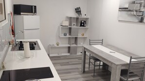 Eine moderne Küche mit einer zentralen Kochinsel, eingebauten Geräten und einem Essbereich mit Tisch und Stühlen.