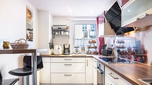 A modern kitchen with white cabinets, a wooden countertop, and a built-in oven. - Apartment 'Terrassenblick' with Mountain View, Private Terrace, and Wi-Fi (Sankt Georgen)