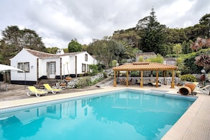 A swimming pool with lounge chairs, a gazebo, and a white house with a tiled roof. - Double Room 3 – Quinta do Rossio - Rural Tourism (Biscoitos)