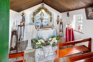 A chapel interior with a wooden altar, religious statues, and floral arrangements. - Double Room 3 – Quinta do Rossio - Rural Tourism (Biscoitos)