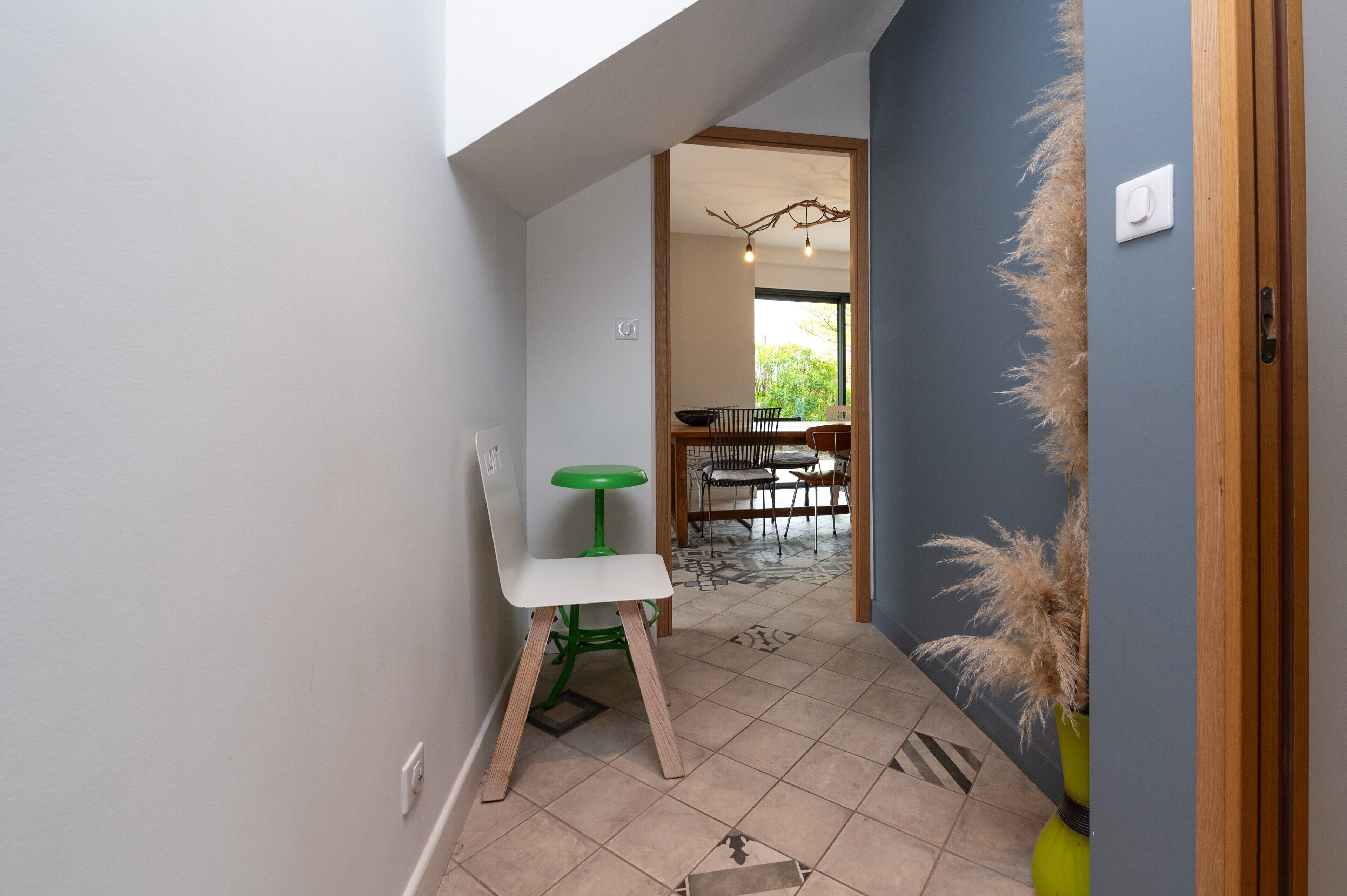 Un couloir comprenant un coin repas, une chaise, une petite table et une plante.