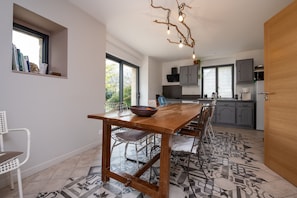 Une cuisine moderne avec une table en bois, des chaises et un luminaire original.