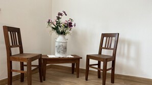 Zwei Holzstühle und ein kleiner Tisch mit einer Blumenvase.