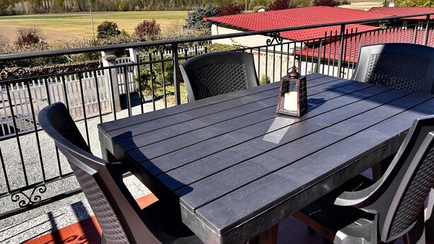 Ein Balkon mit Tisch und Stühlen, einer Laterne und Blick auf schneebedeckte Berge.