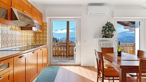 Une cuisine dotée de meubles en bois, d’une hotte de cuisinière en acier inoxydable et d’une grande fenêtre offrant une vue sur les montagnes.