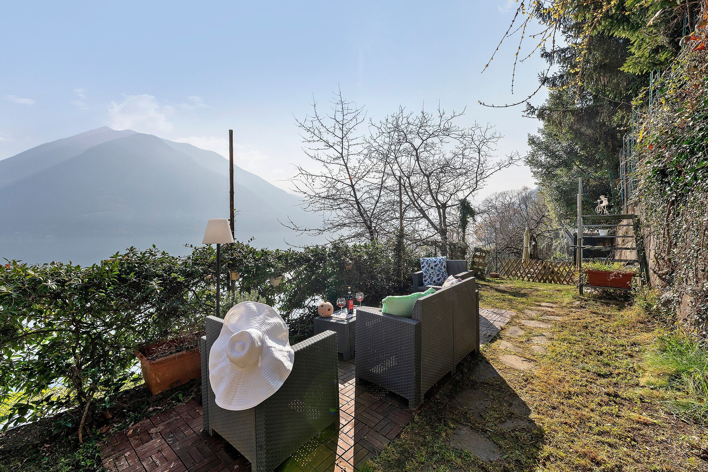 An outdoor seating area with wicker furniture, a potted plant, and a view of a mountain.