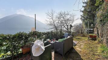 An outdoor seating area with wicker furniture, a potted plant, and a view of a mountain.