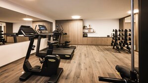 Een sportschool met loopbanden, elliptische trainers en een rek met gewichten.