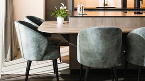 Een moderne keuken met donkere kastjes, een houten kookeiland en twee gestoffeerde stoelen.