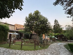Un cortile con sentieri in pietra, recinzioni in legno rustico e edifici tradizionali.