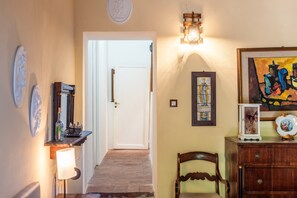 Un couloir avec un banc en bois, une porte et un luminaire fixé au mur.