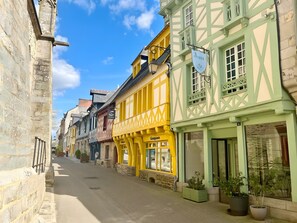 Eine schmale Straße, gesäumt von traditionellen Fachwerkhäusern, einige davon mit Schilder, die Geschäfte kennzeichnen.