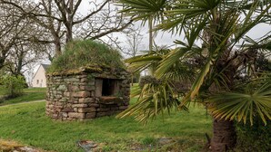 A stone structure with a small opening, surrounded by grass and trees. - Holiday Home Gîte La Colombe - Les Hortensias (La Croix-Helléan)