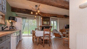 A kitchen with a dining area, wooden ceiling beams, and a view to the outside. - Holiday Home Gîte La Colombe - Les Hortensias (La Croix-Helléan)
