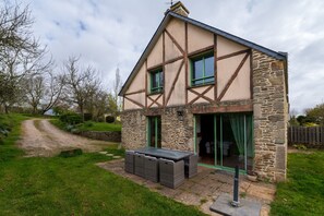 Ein zweistöckiges Haus mit Natursteinfassade, geneigtem Dach und einer großen Schiebeglastür.