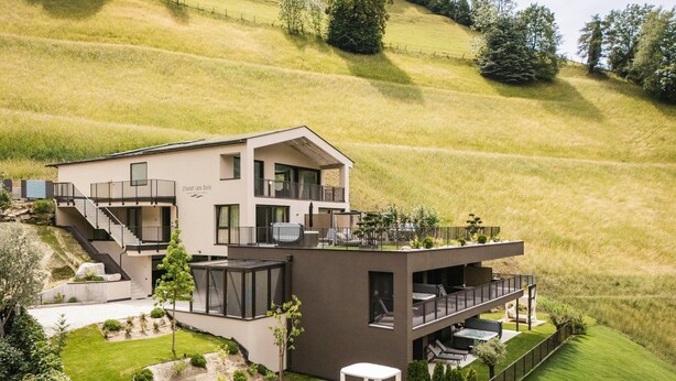 A modern two-story house with a balcony, a staircase, and a small garden area. - Apartment 'Les Ovis Comisana' – Opening May 2026 with Private Jacuzzi (San Leonardo in Passiria)