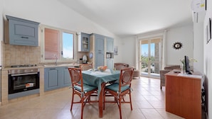A kitchen with a dining table, chairs, and a small island. - Casa Valeria – Residence Valentina, beachfront in Balestrate (Balestrate)