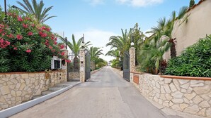 A street leading to a gated entrance with stone walls and palm trees. - Casa Valeria – Residence Valentina, beachfront in Balestrate (Balestrate)