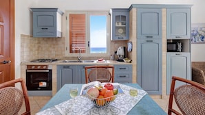A kitchen with a dining table, chairs, a stove, and a view of the sea. - Casa Valeria – Residence Valentina, beachfront in Balestrate (Balestrate)