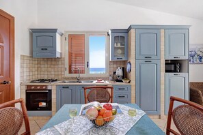 Une cuisine équipée d’une table à manger, de chaises, d’une cuisinière et offrant une vue sur la mer.