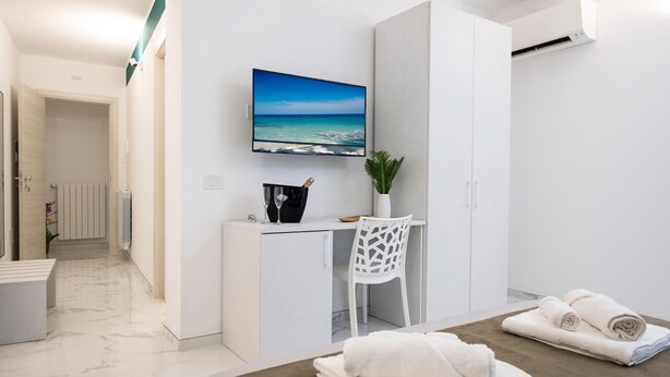 Een moderne hotelkamer met een bed, een bureau, een stoel, een televisie en uitzicht op de oceaan.