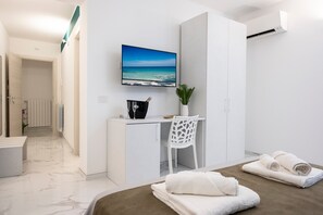Een moderne hotelkamer met een bed, een bureau, een stoel, een televisie en uitzicht op de oceaan.