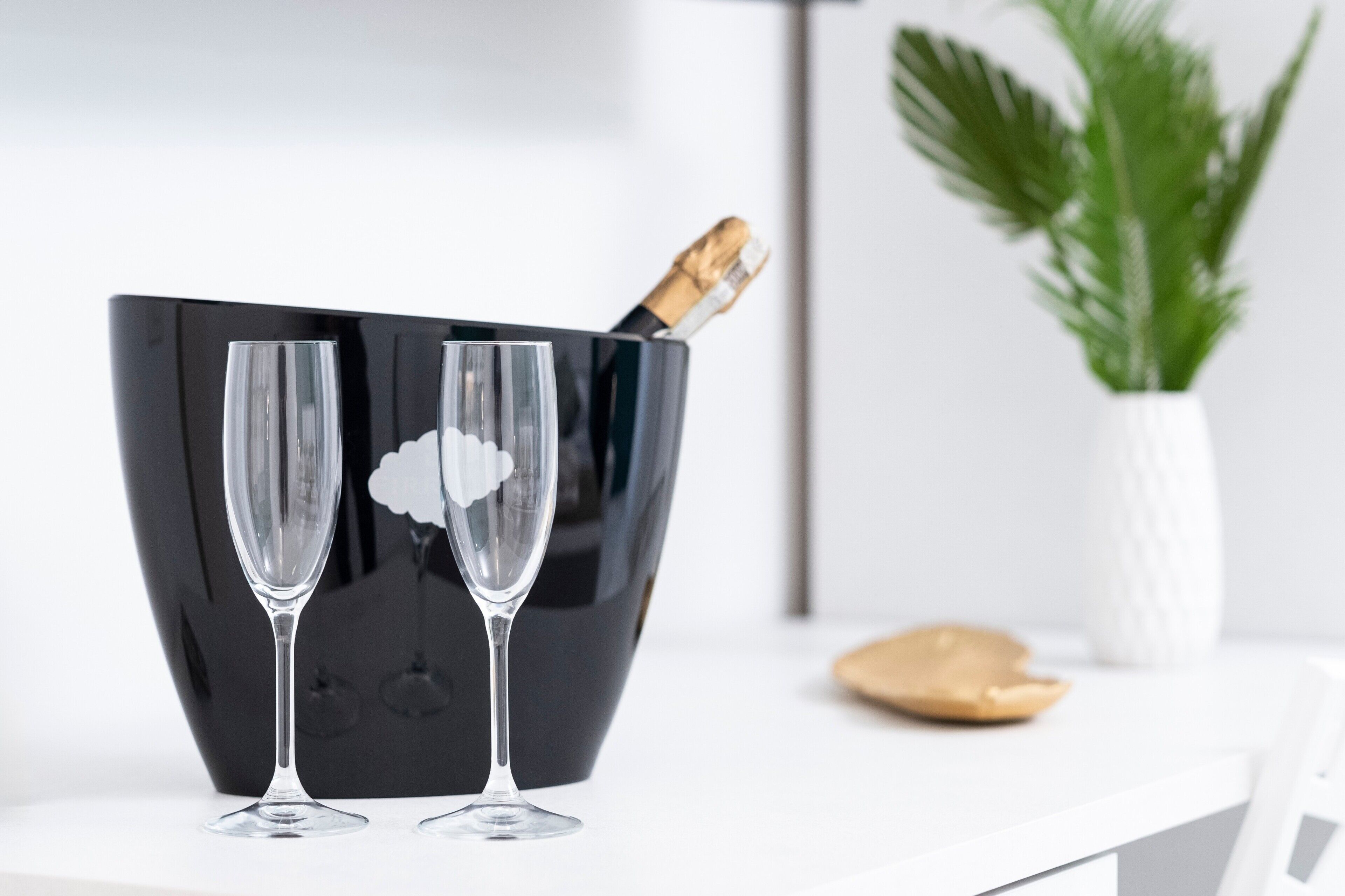 Un seau noir contenant deux verres transparents et une bouteille de champagne.