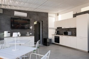 Eine moderne Küche mit weißen Schränken, ein Essbereich mit Tisch und Stühlen sowie eine Decke mit linearer Gestaltung.