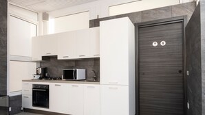 Een moderne keuken met witte kastjes, een magnetron, fornuis en oven.
