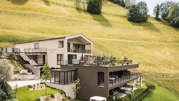 Ein modernes, zweistöckiges Haus mit Balkon, Treppe und kleinem Garten.