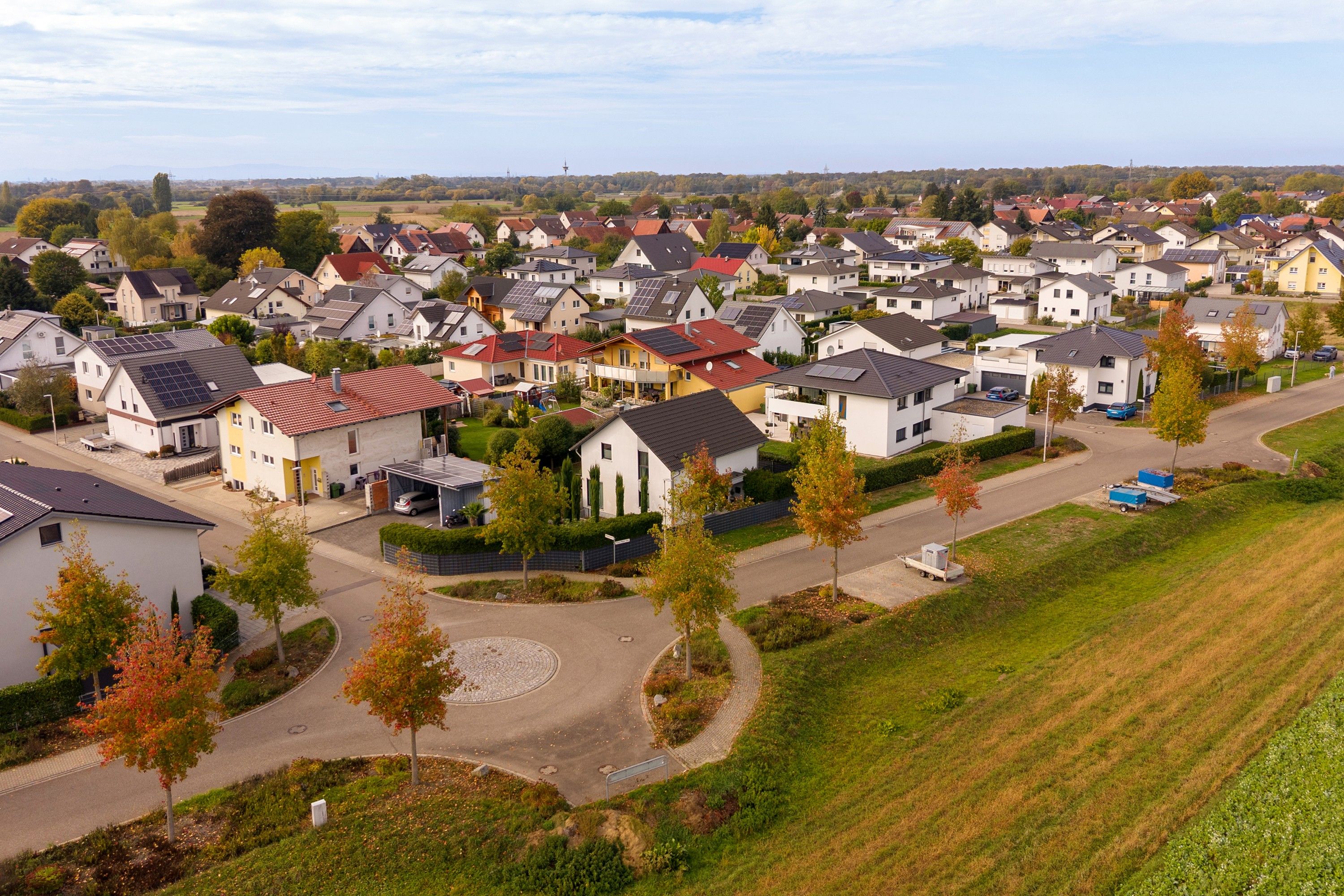 Ein Wohngebiet mit Häusern, Straßen und einem grünen Feld.