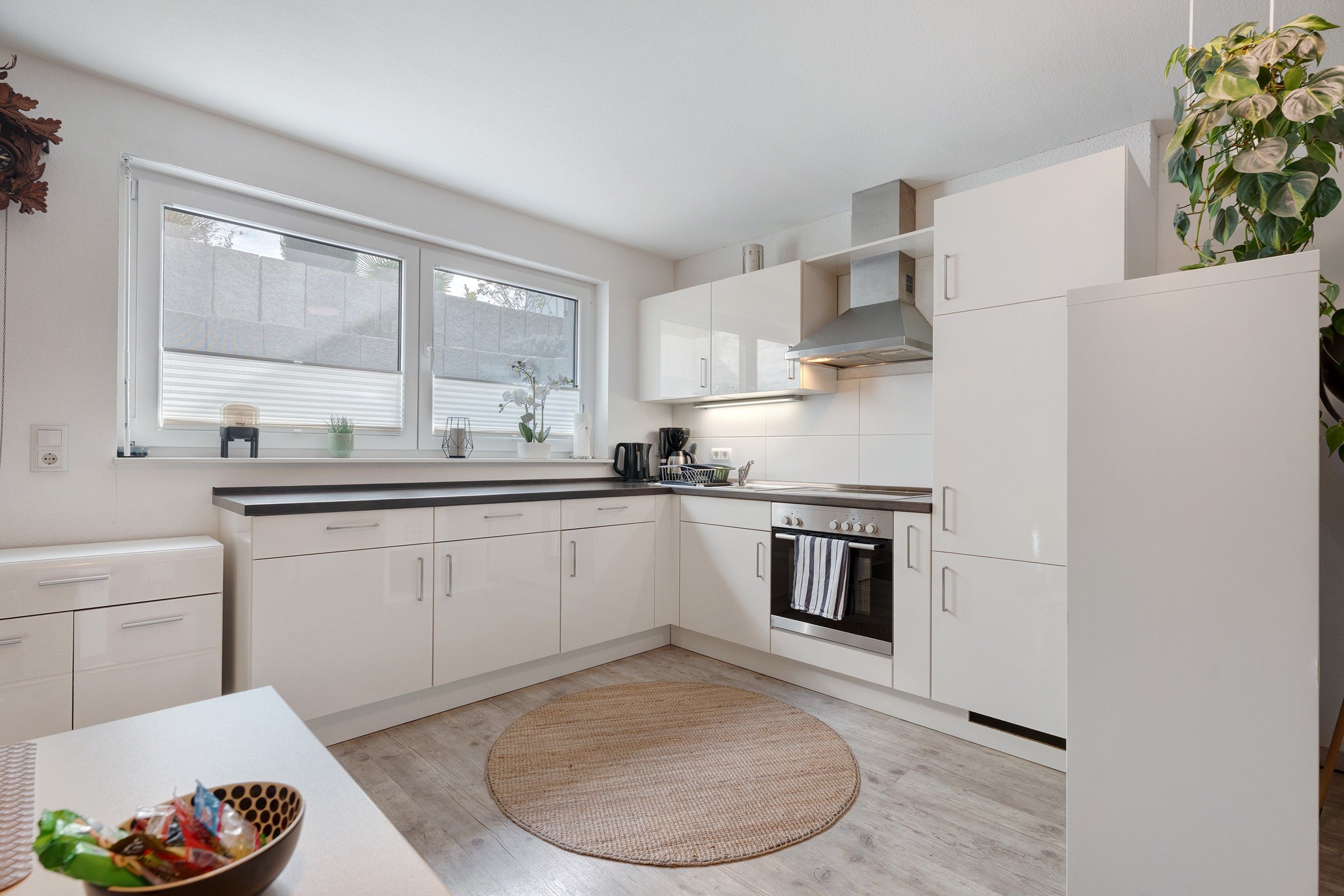 Eine moderne Küche mit weißen Schränken, einem eingebauten Backofen und einem großen Fenster.