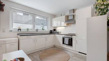Eine moderne Küche mit weißen Schränken, einem eingebauten Backofen und einem großen Fenster.