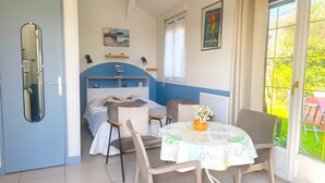 Une chambre à coucher comprenant un lit, des tables de chevet, une chaise, une table avec un vase et une fenêtre donnant sur un beau paysage.