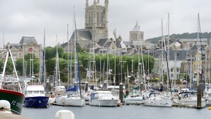 Un port de plaisance où sont amarrés de nombreux bateaux, un bâtiment historique en arrière-plan et un ciel dégagé.