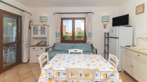 Une chambre à coucher comprenant un lit, un bureau, une chaise, un téléviseur et une fenêtre avec des rideaux.