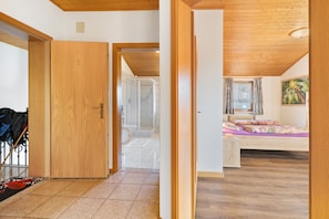 A room with a bed, a window with curtains, a radiator, and a door leading to another room. - Apartment 1 Lindebauer in Tyrol – Mountain View, Balcony, Wi-Fi (Tirol)