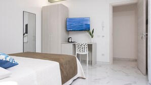 A bedroom with a bed, a desk, a chair, a TV, and a wardrobe.