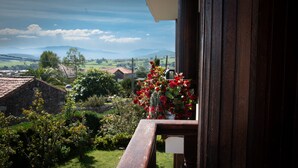 A balcony with a view of a rural landscape, including houses and hills.