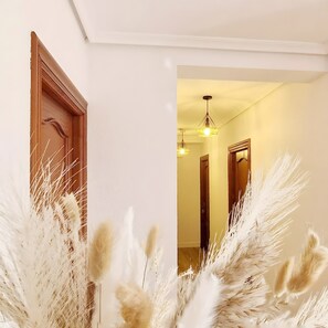 A hallway with a wooden door, a white wall, and a ceiling light fixture.