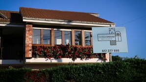 A building with a sign for 'COSMAHOUSE bed & breakfast' and a contact number.