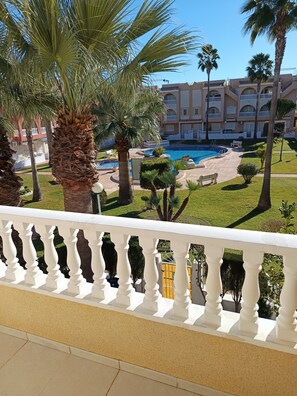 Ein Hotel mit Pool, Palmen und einem gepflegten Rasen.