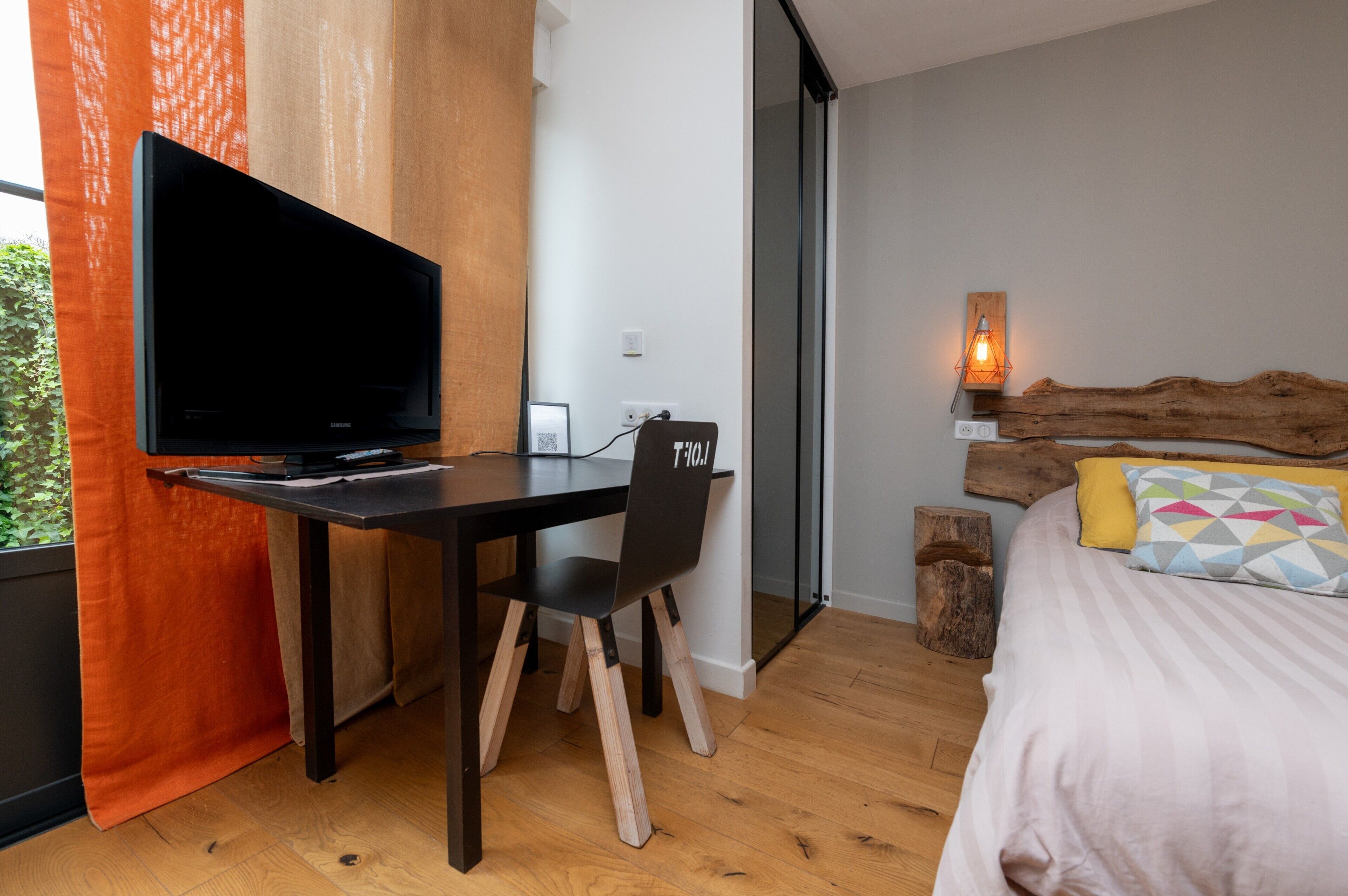 Un dormitorio moderno con cama, televisor, escritorio y silla.