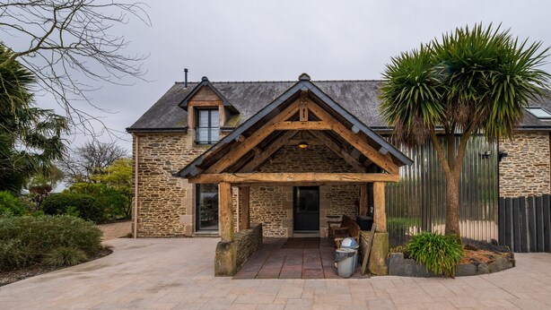 A stone building with a wooden porch, a door, and a small window.