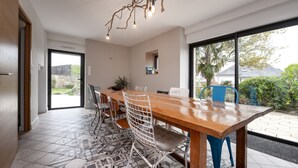 A modern kitchen with a wooden table, white chairs, and a large window.