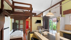 A room with a bed, a small bar area with a stool, a television, and a view of the outside.