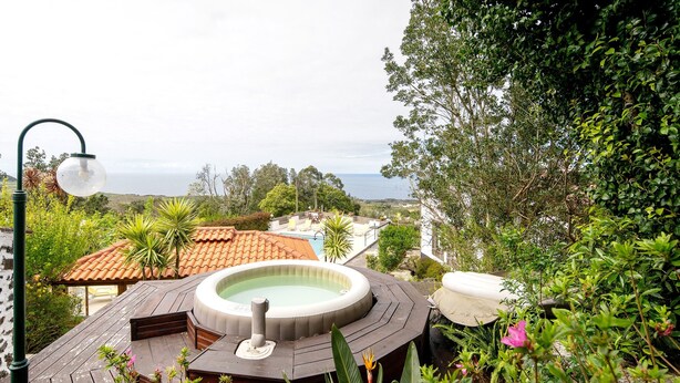 A hot tub on a wooden deck with a view of the ocean.
